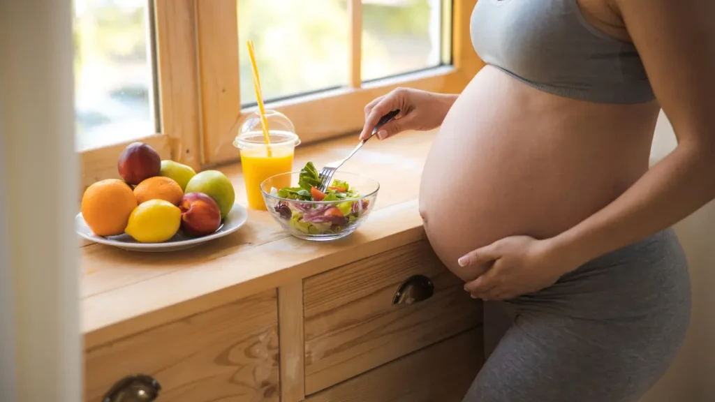 grávida em pé com mão na barriga comendo